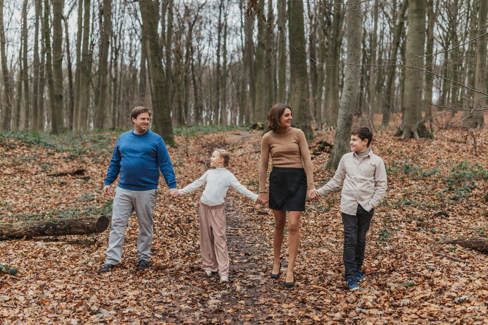 Family enjoying a casual walk together in a wooded area during fall.