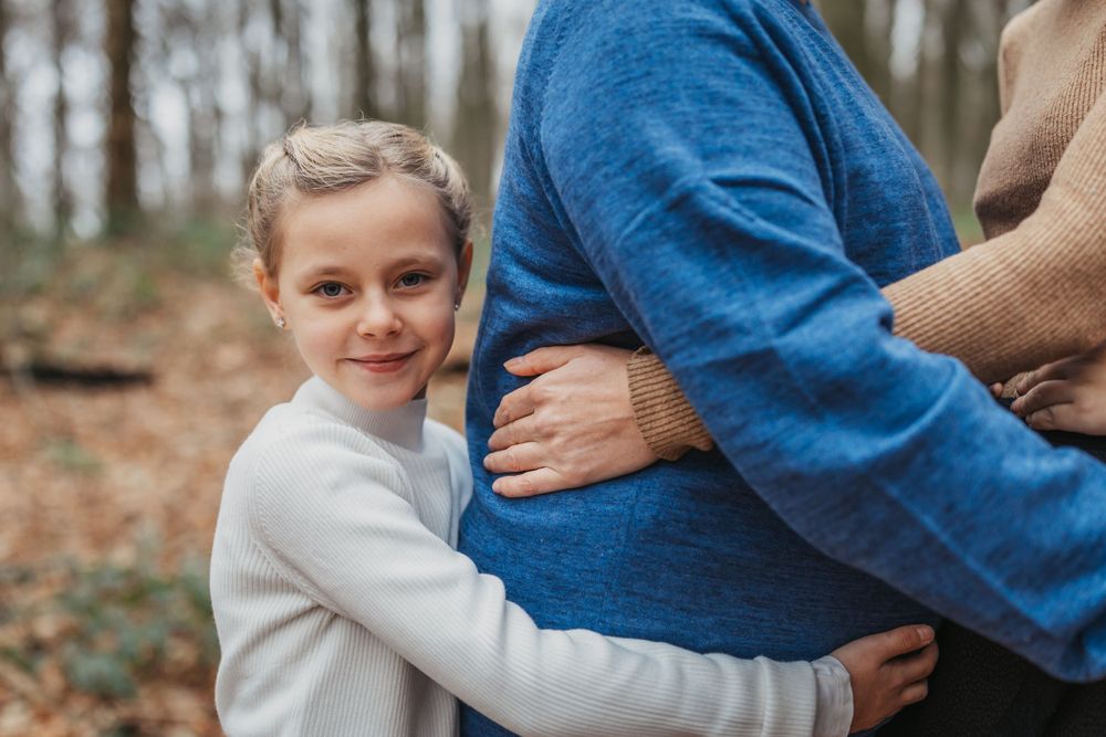 An affectionate family moment captured in a forest with fallen autumn leaves.