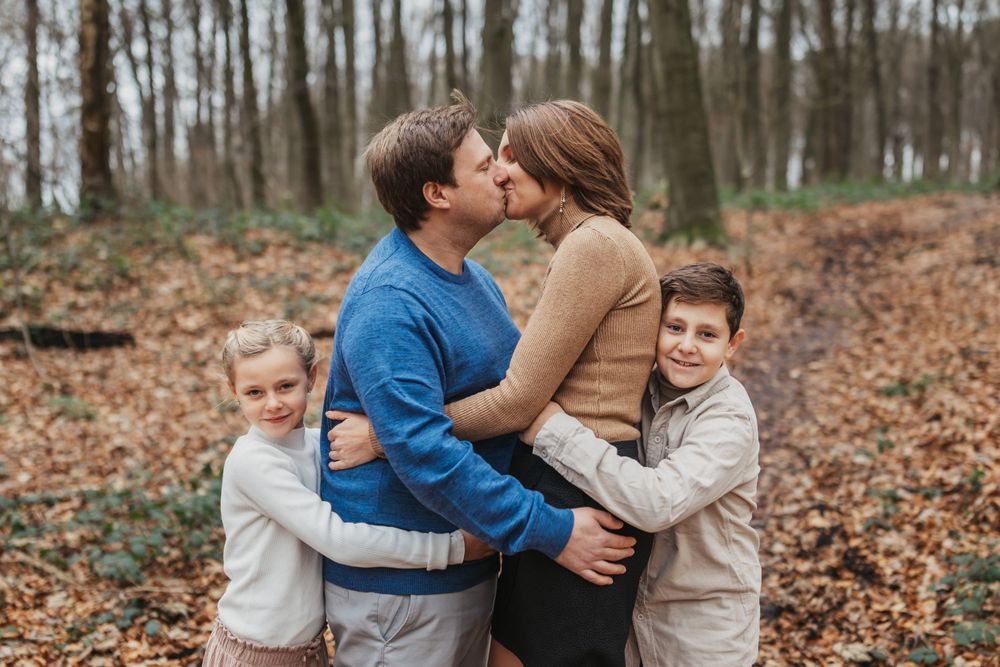 Intimate family moment captured in a forest setting during autumn.
