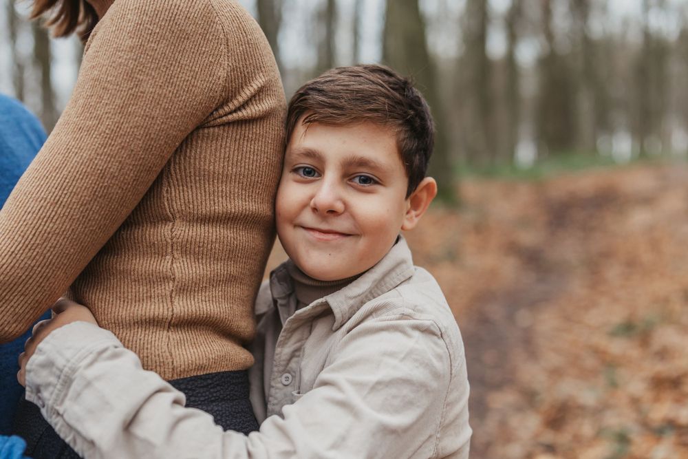 A warm embrace captured in an autumn forest setting with fallen leaves on the ground.