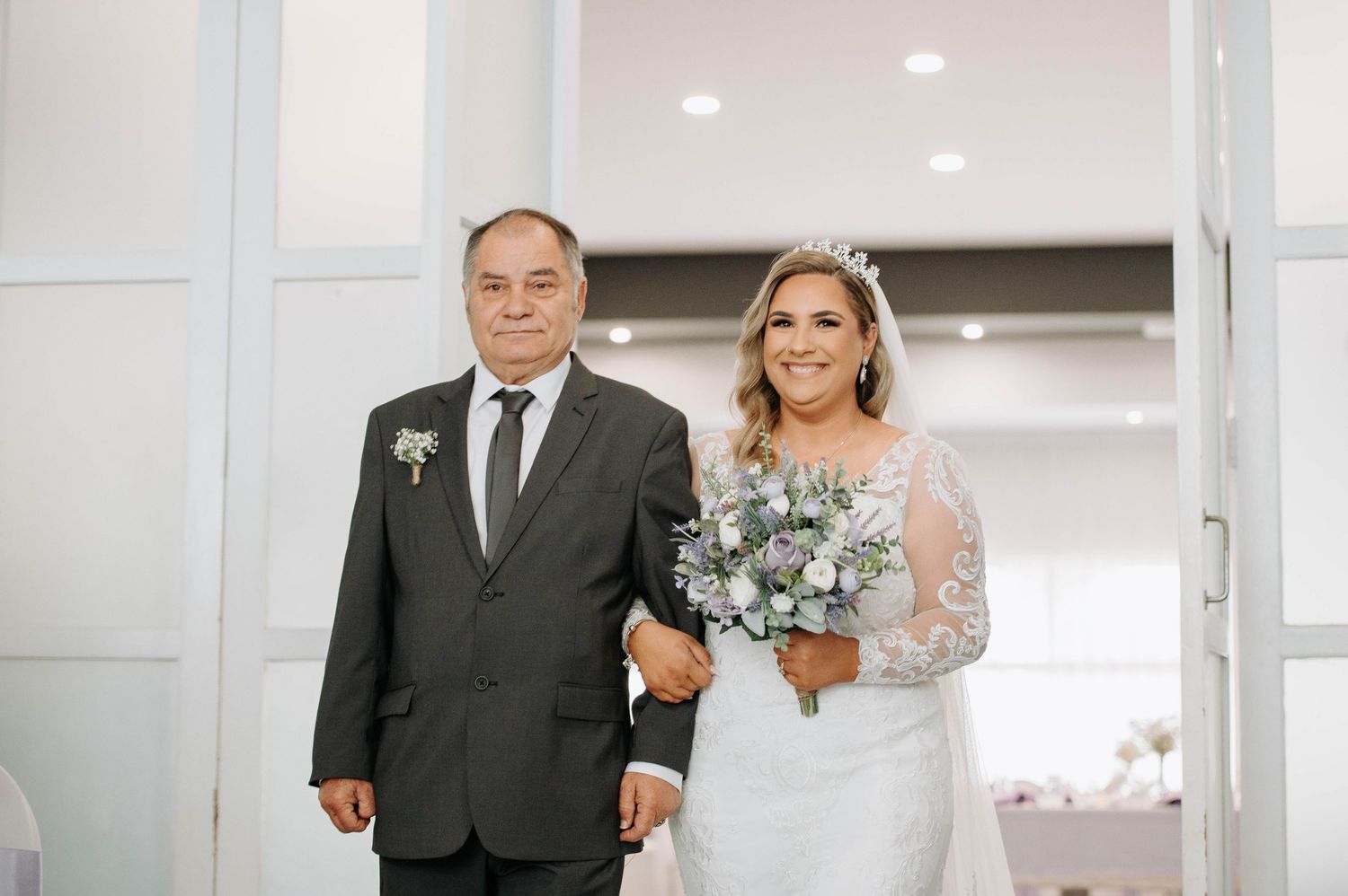 Walking down a hallway together at a wedding venue while linked arm in arm.