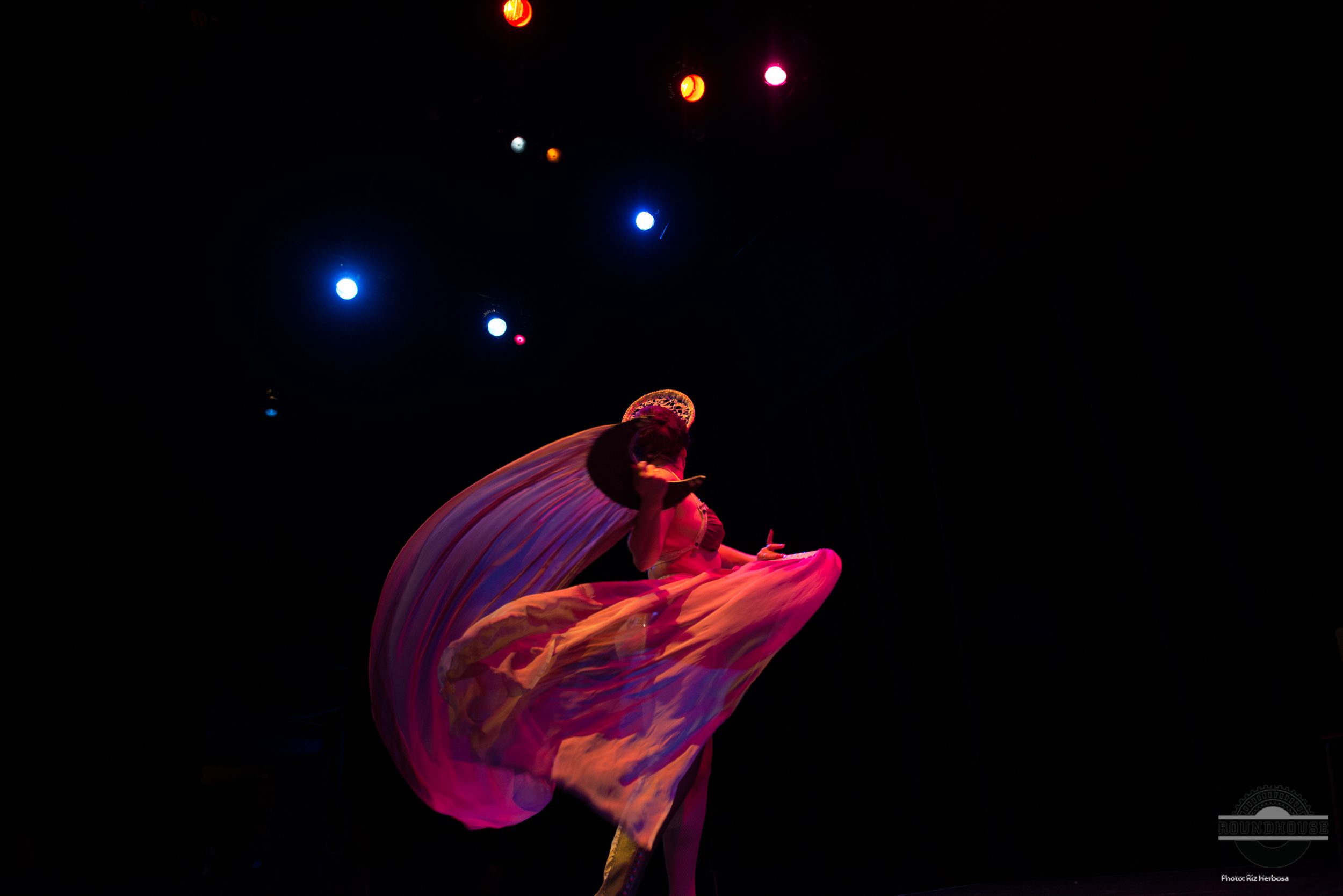A dancer creates a swirling motion with flowing pink fabric under theatrical lighting during the Beerlesque Event in Vancouver.