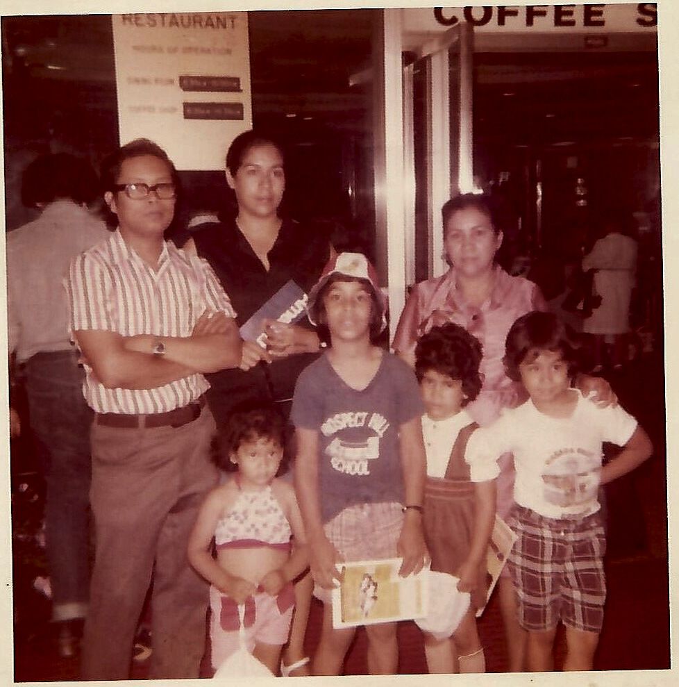 Vintage sepia photograph showing a family gathering at a coffee shop or restaurant in the 1970s.