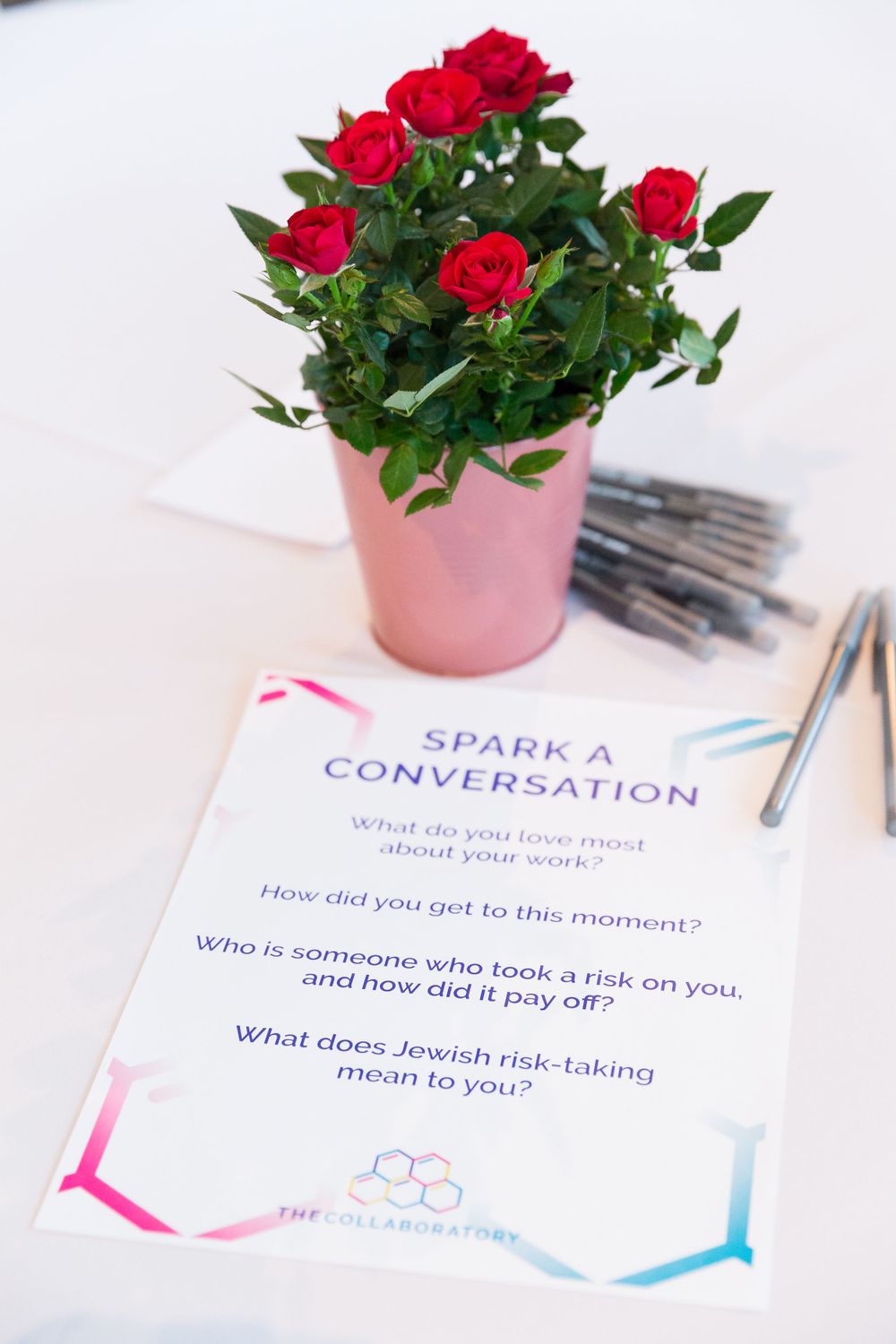 Red roses in a pink pot next to a 'Spark a Conversation' discussion card.