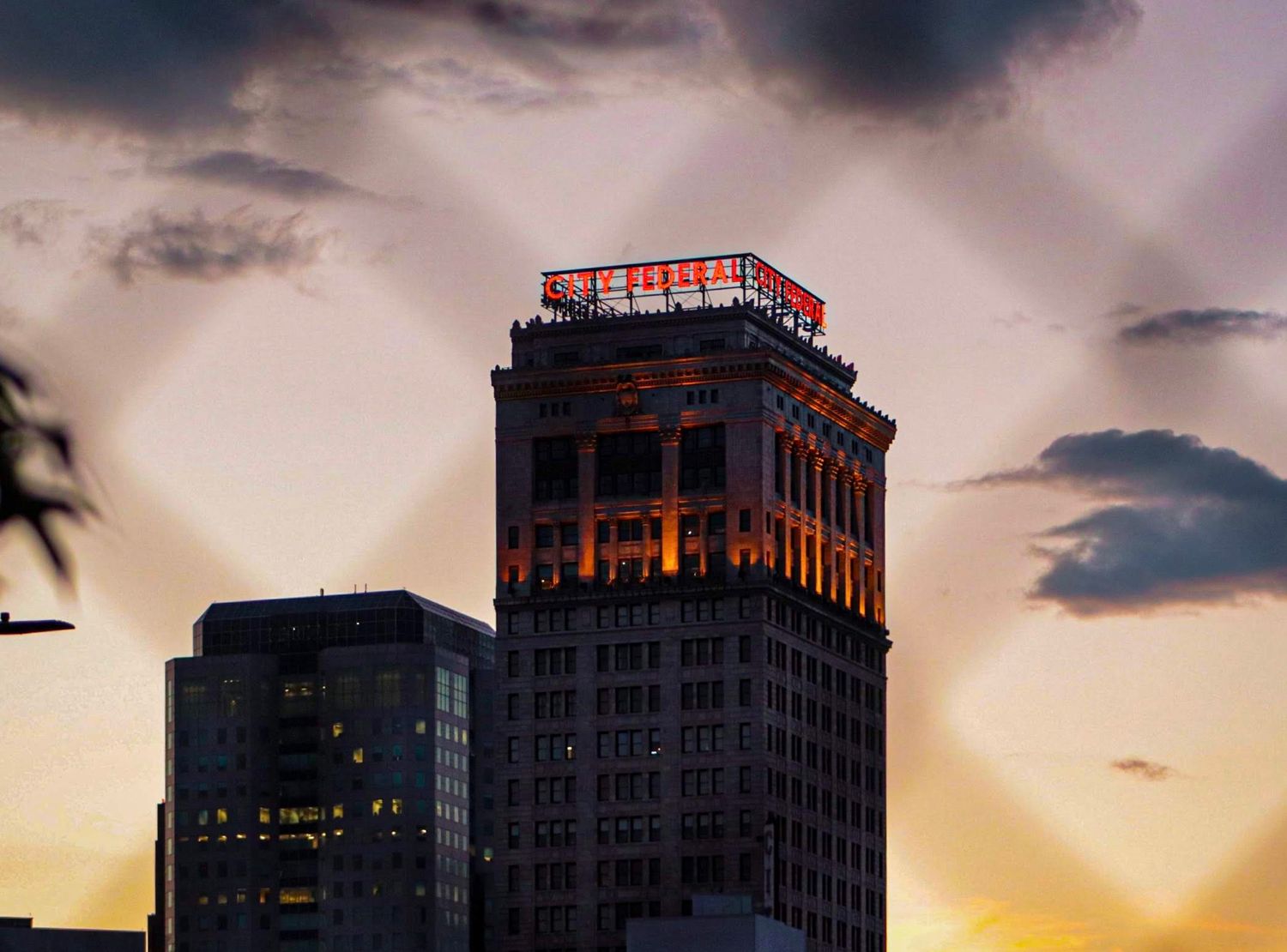 Urban skyscraper silhouetted against dramatic sunset sky.
