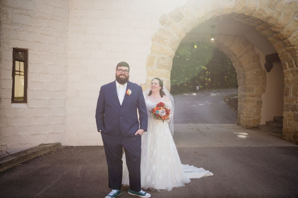 Couple stands under stone archway during wedding ceremony at historic venue.