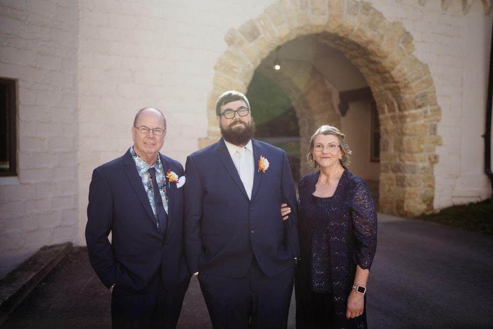 Family formal portrait taken under stone archway at wedding venue.