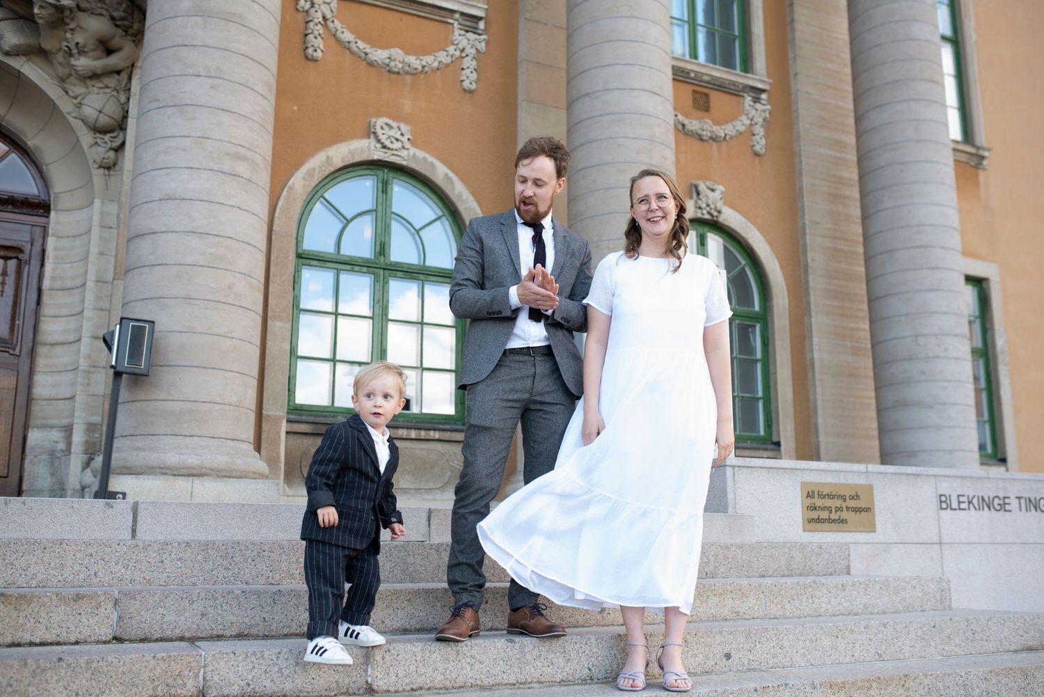 Family portrait on ornate building steps with classical architecture.