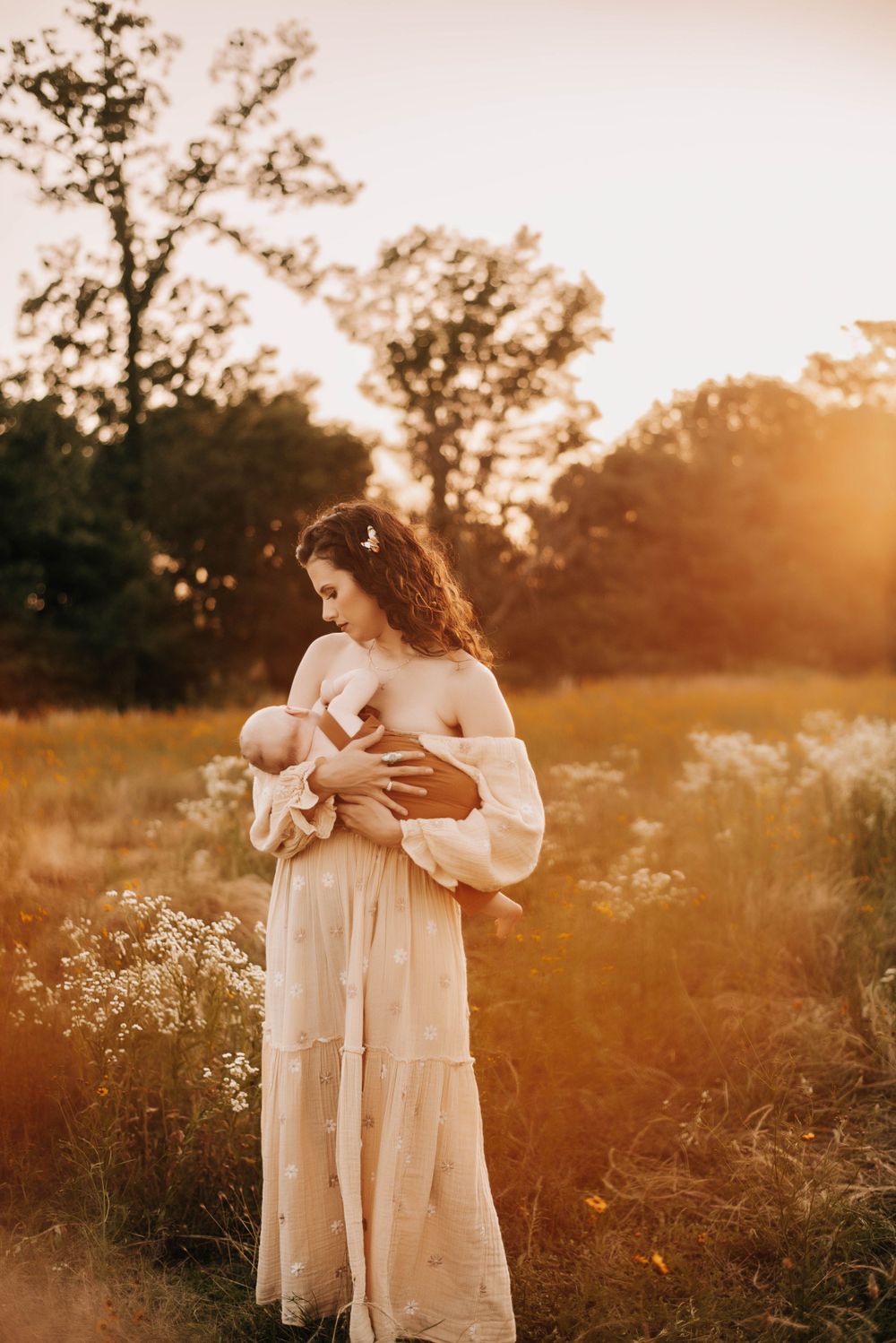 Mother and child embrace in golden wildflower field at sunset.