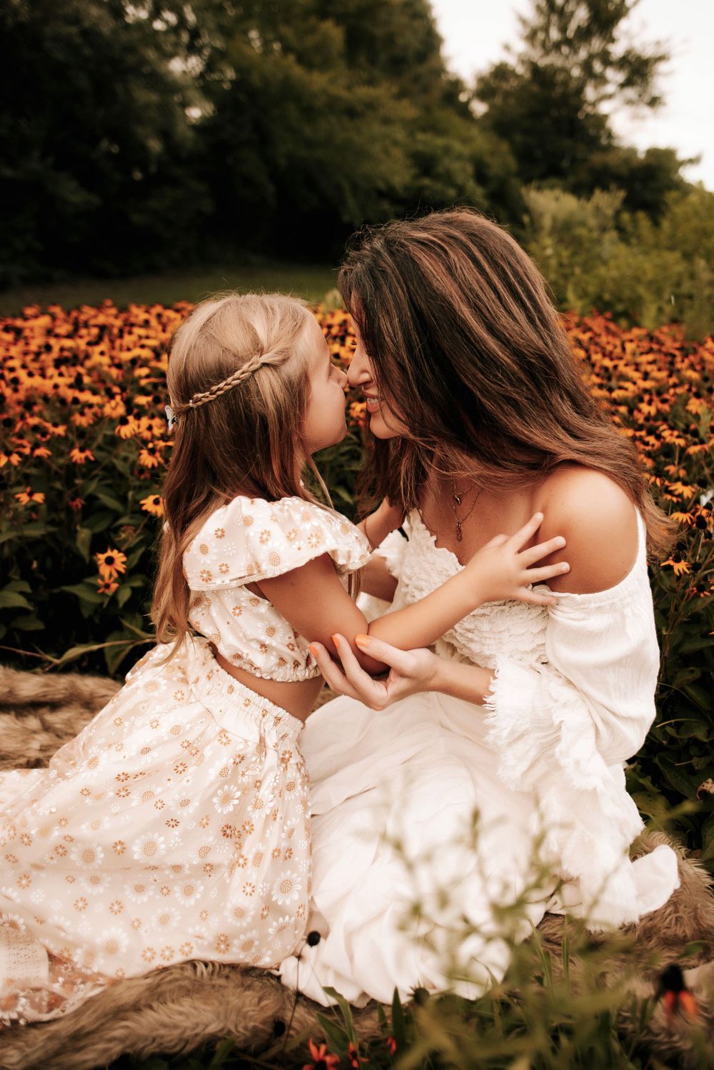 Two people in white lace dresses lying among orange wildflowers.