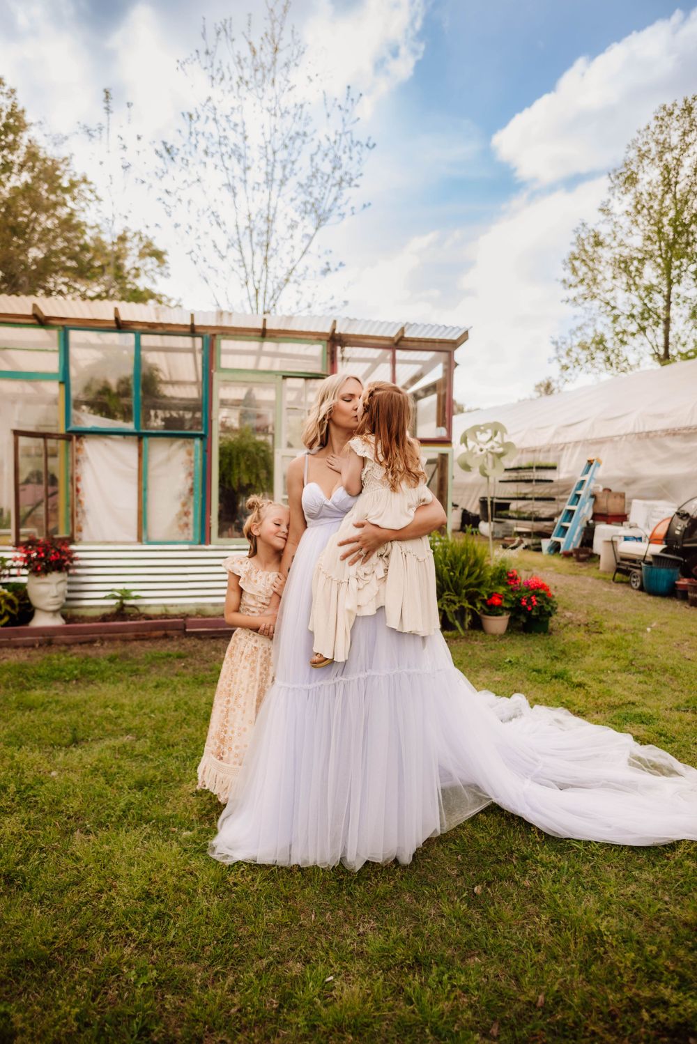 Family in flowing dresses dancing together outdoors near rustic buildings.
