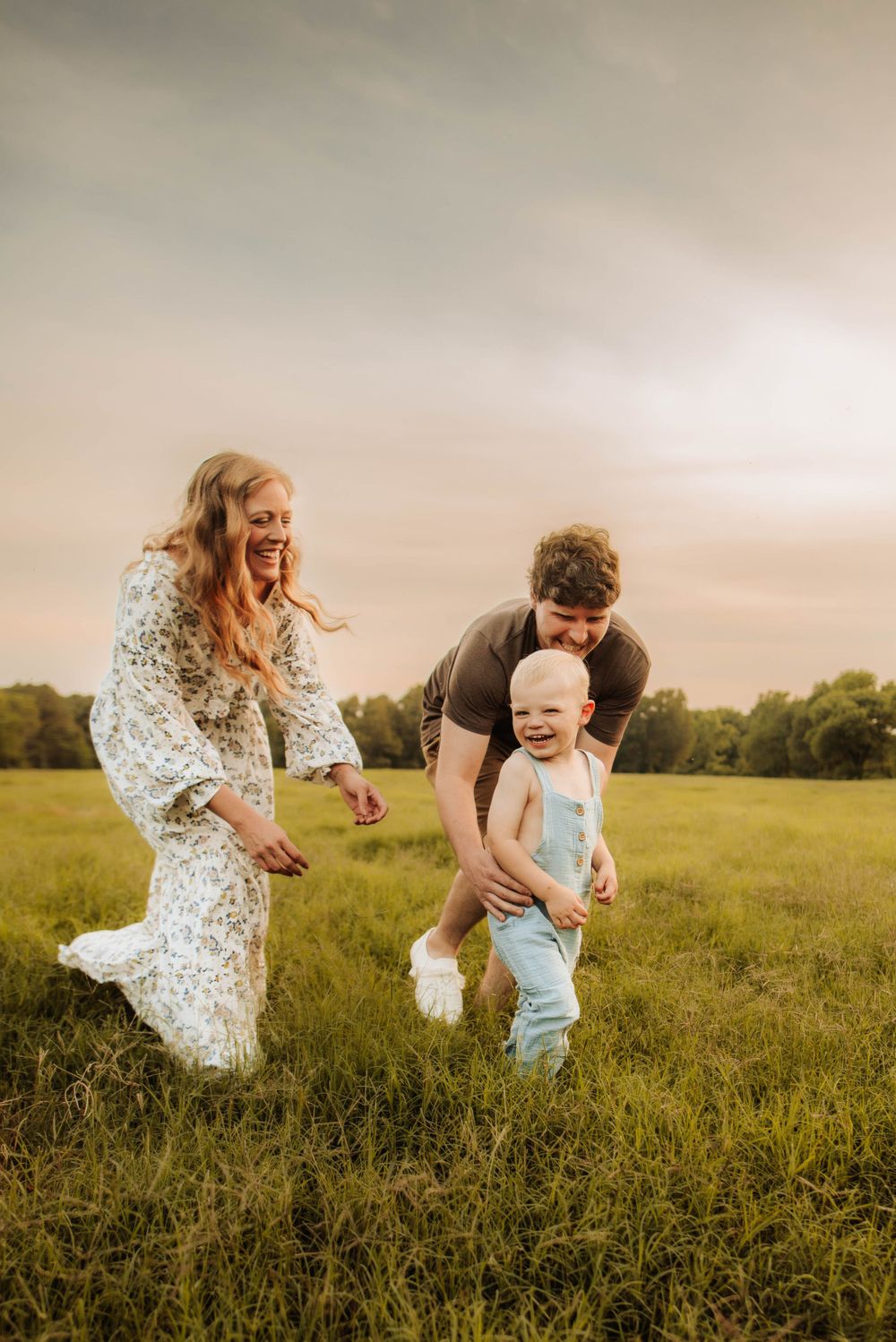 Family playing and laughing together in a green summer meadow.