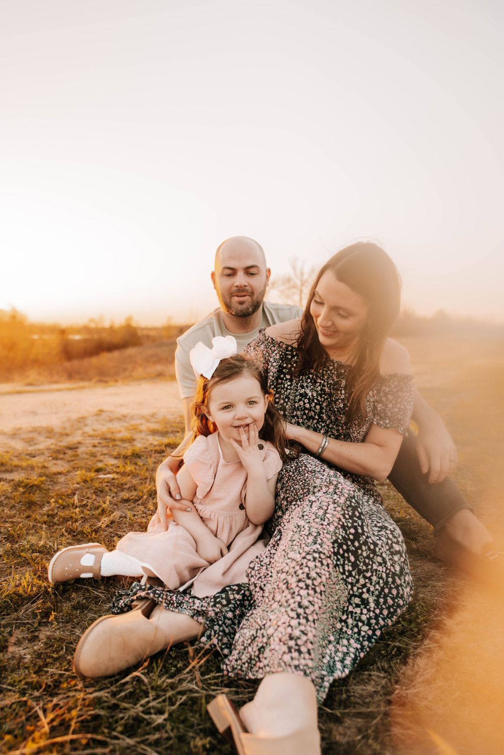Family sitting together on ground during golden sunset in outdoor setting.