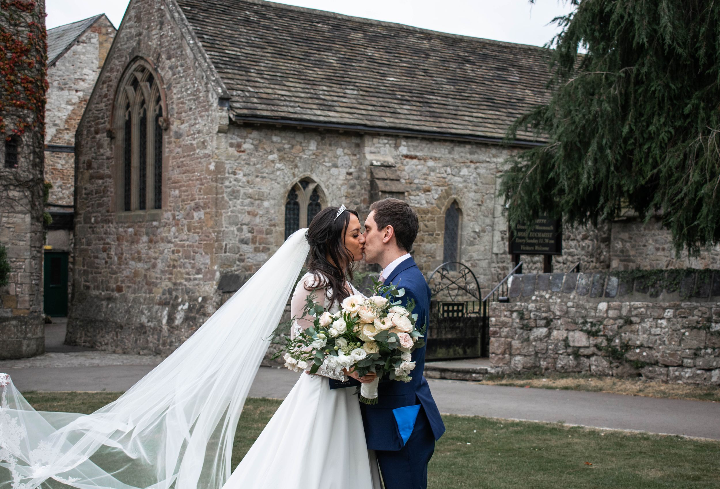 Wind-swept cathedral veil moment against historic stone church architecture.