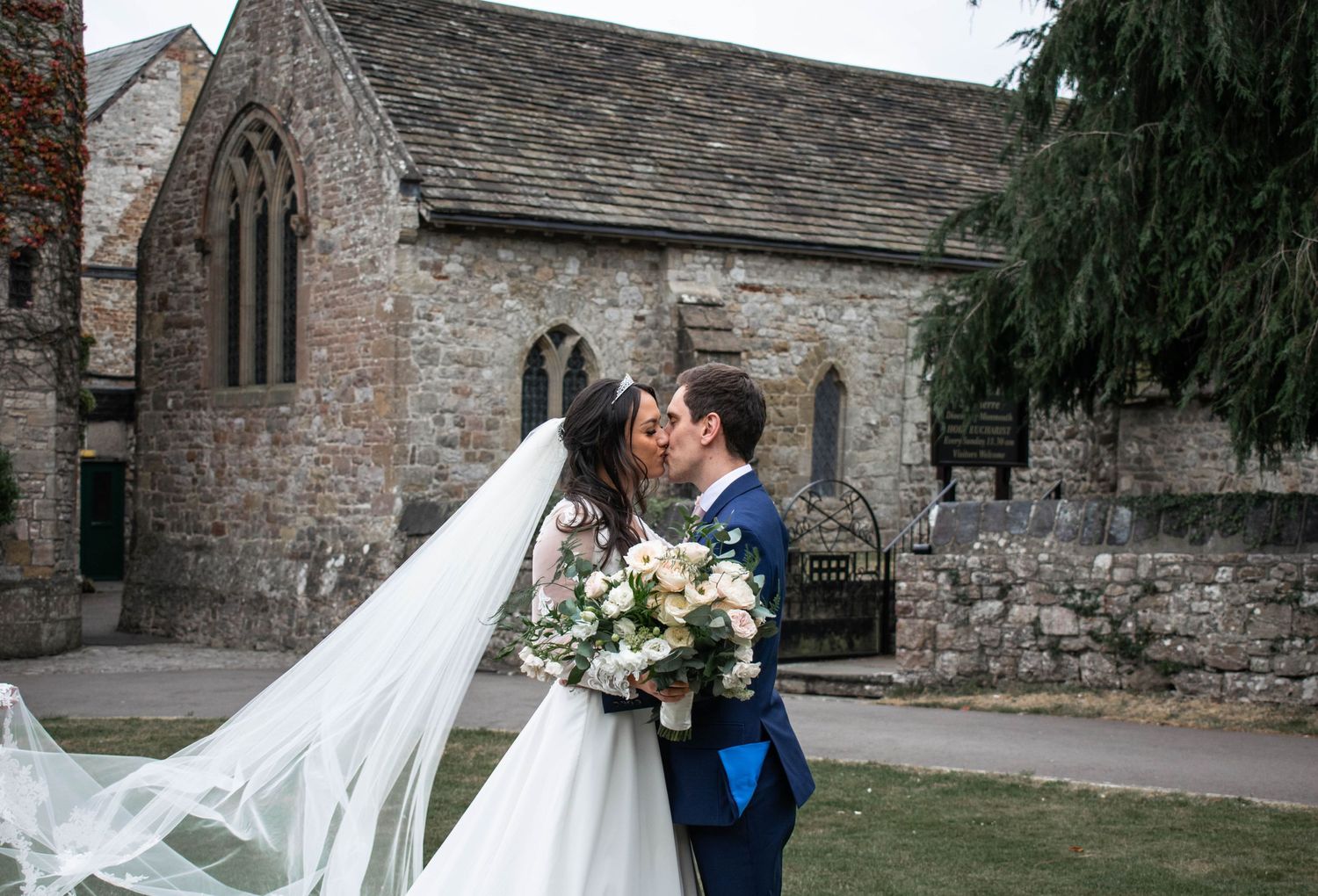 Wind-swept cathedral veil moment against historic stone church architecture.