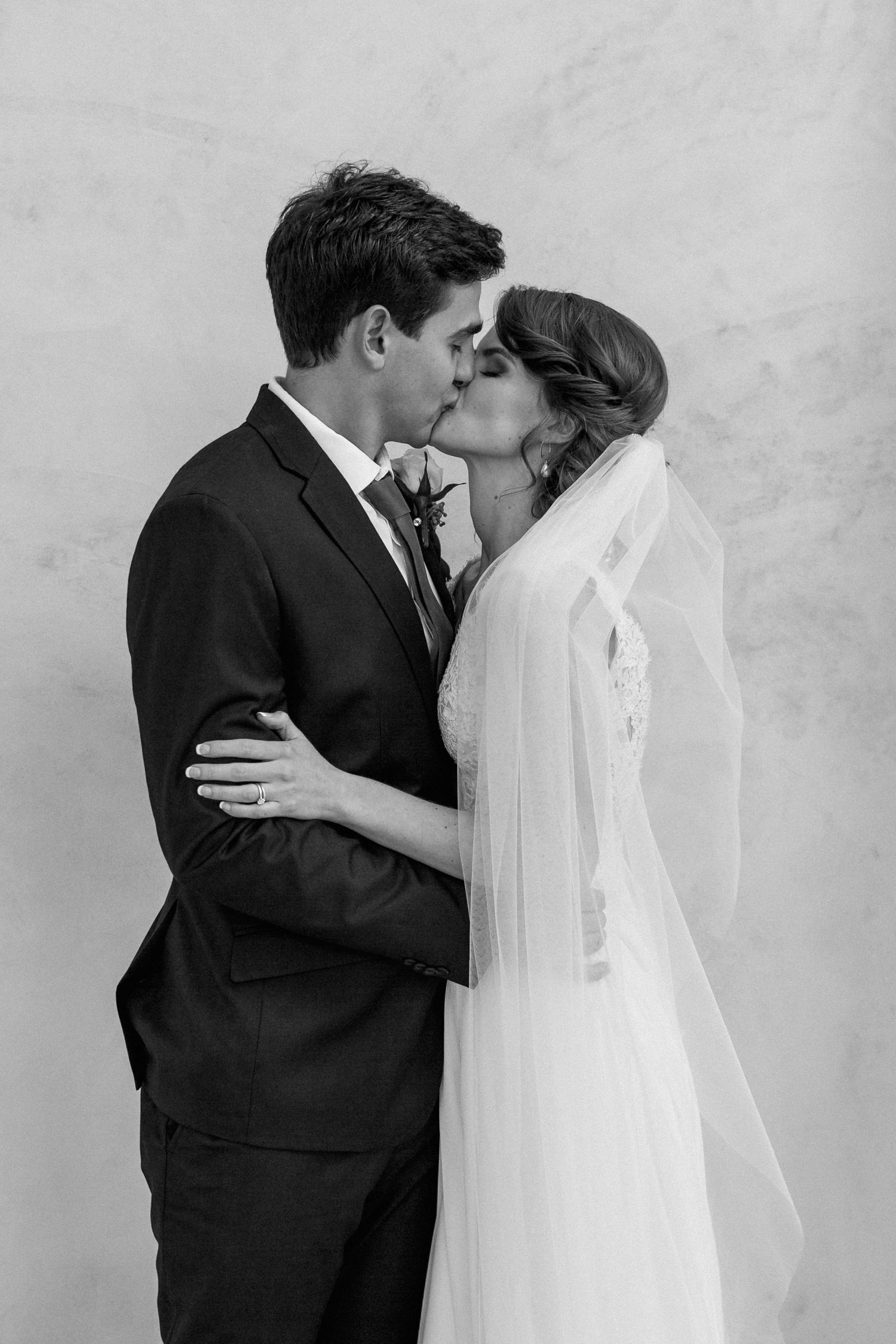 Minimalist black and white moment of a bride and groom kissing