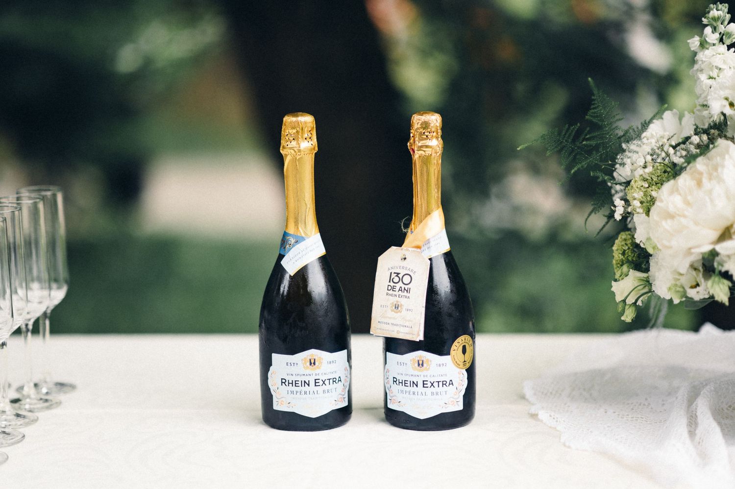 Two bottles of champagne displayed on white tablecloth at outdoor celebration.