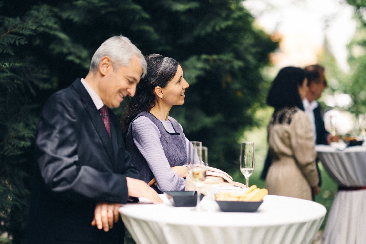 Guests enjoying refreshments at a cocktail table during an outdoor event.