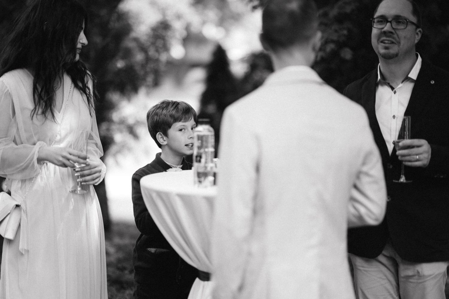 Black and white candid shot of guests mingling at an outdoor reception.