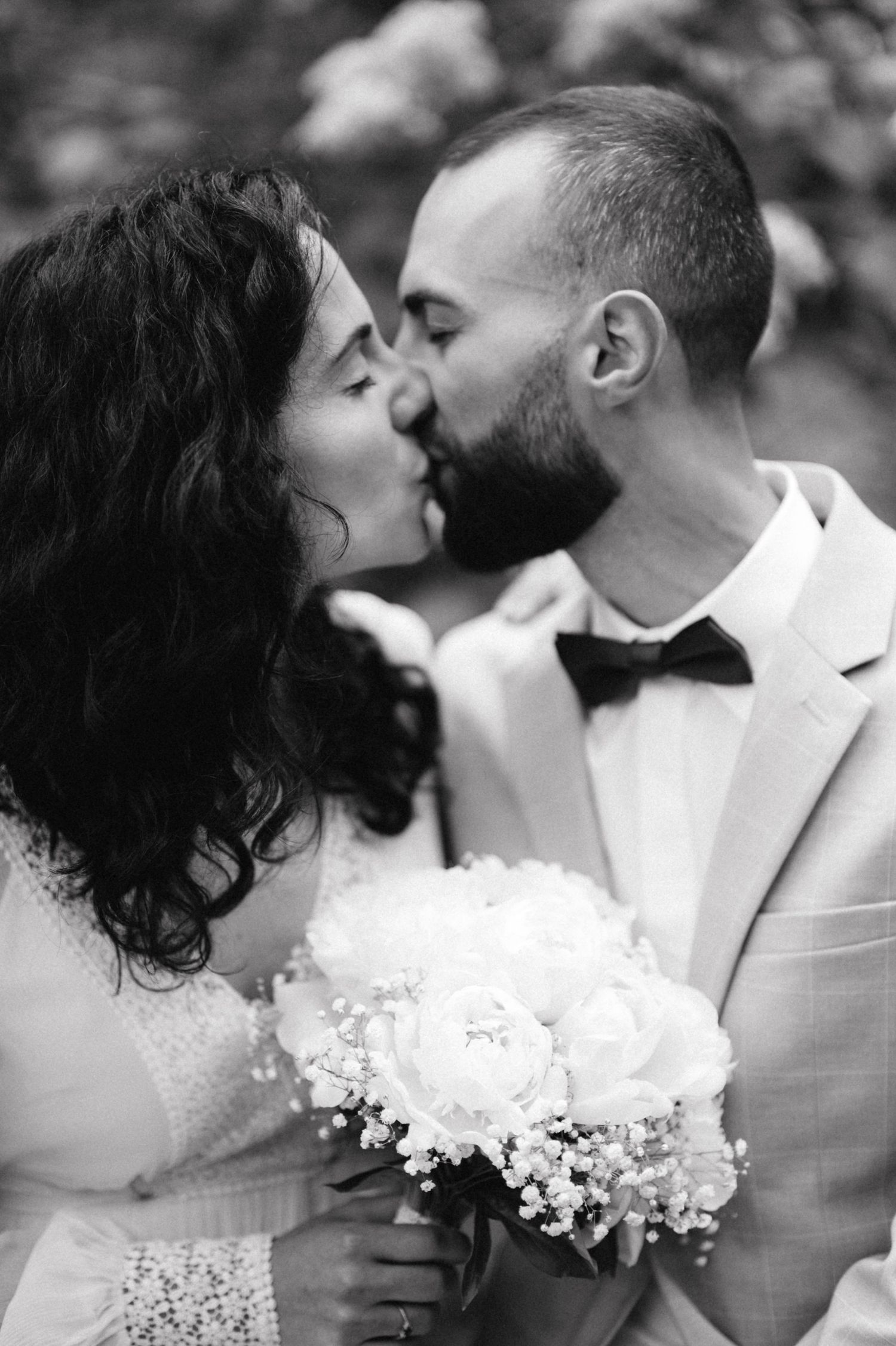 Black and white romantic portrait of newlyweds sharing a kiss.