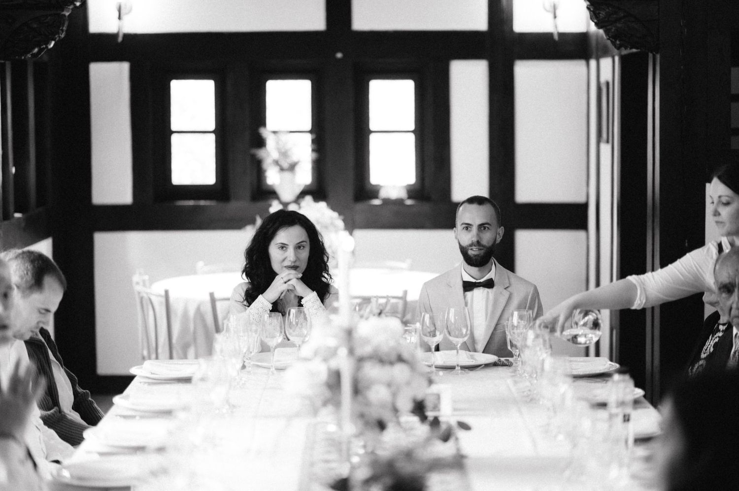 Black and white photo of dinner guests gathered around an elegant table setting.