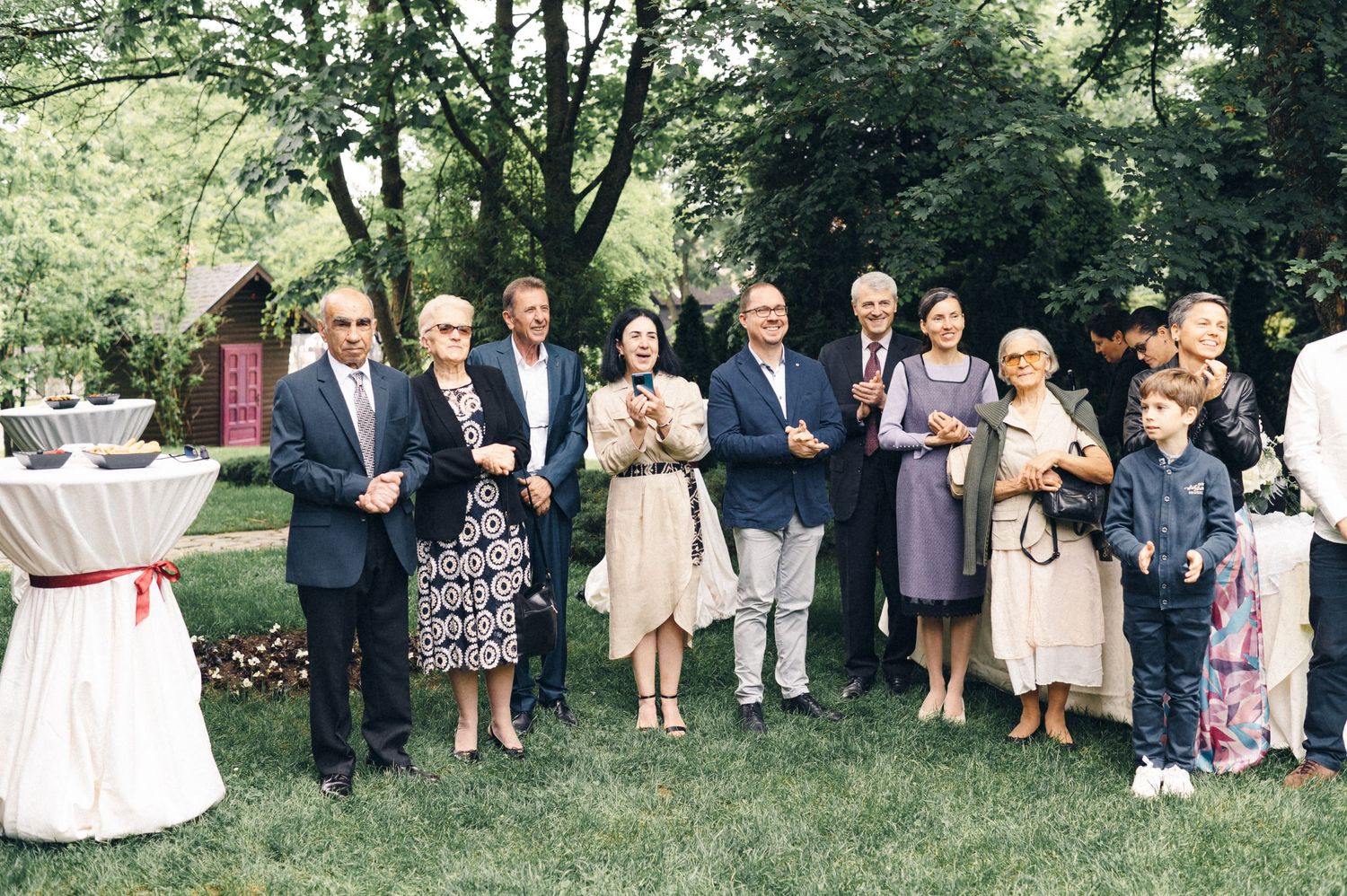 Wedding guests gathered on a lawn during an outdoor summer ceremony with casual garden party atmosphere.