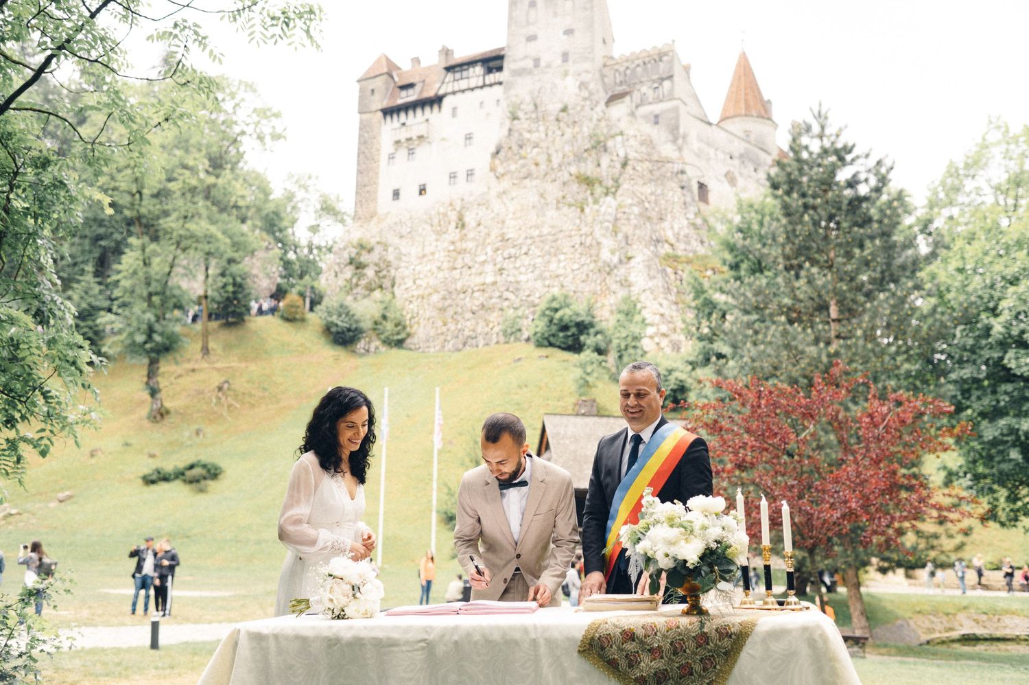 Outdoor wedding ceremony setup near a historic castle with table and floral decorations.