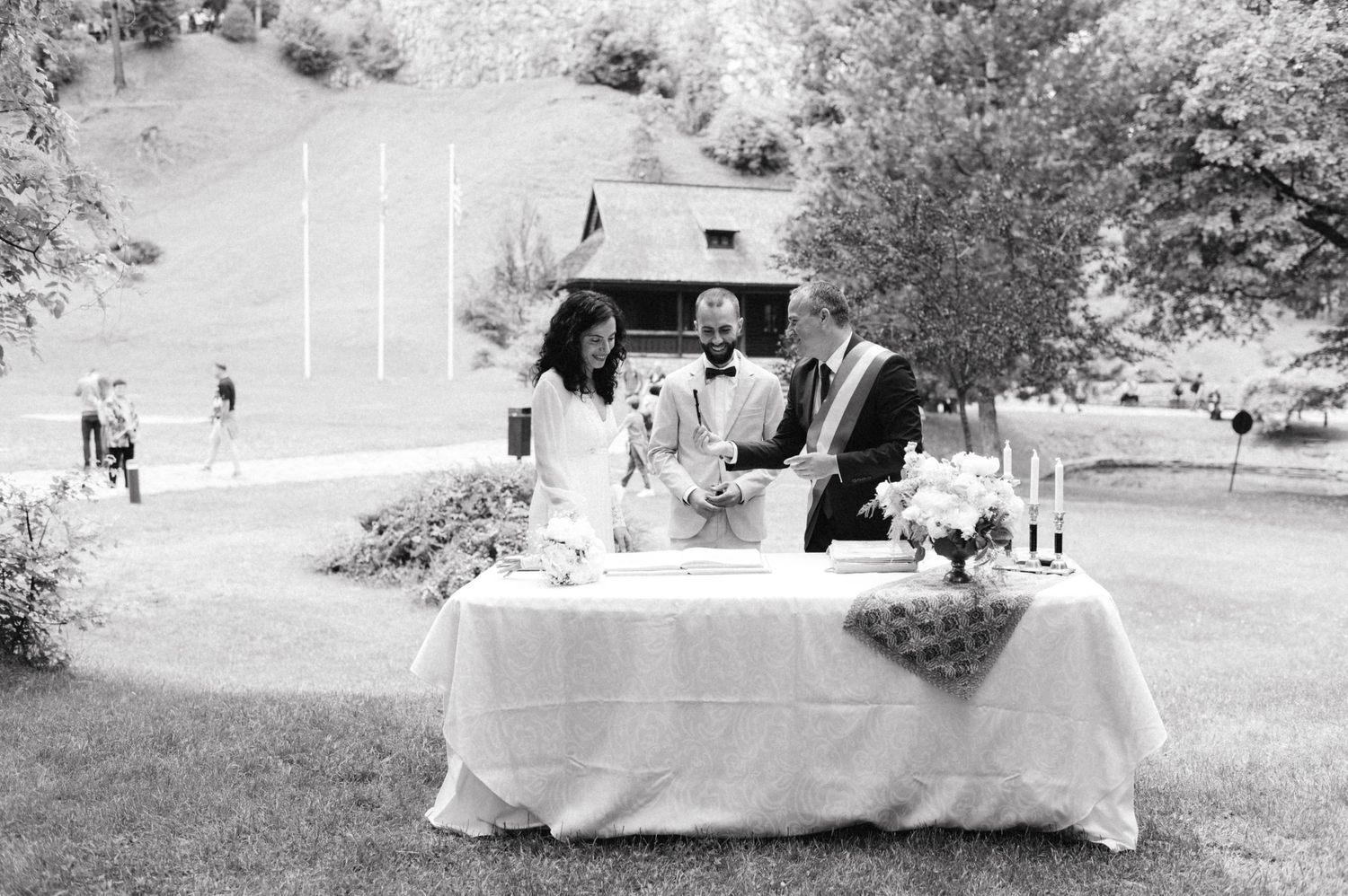 Black and white photo of outdoor wedding reception with table setup in garden setting.