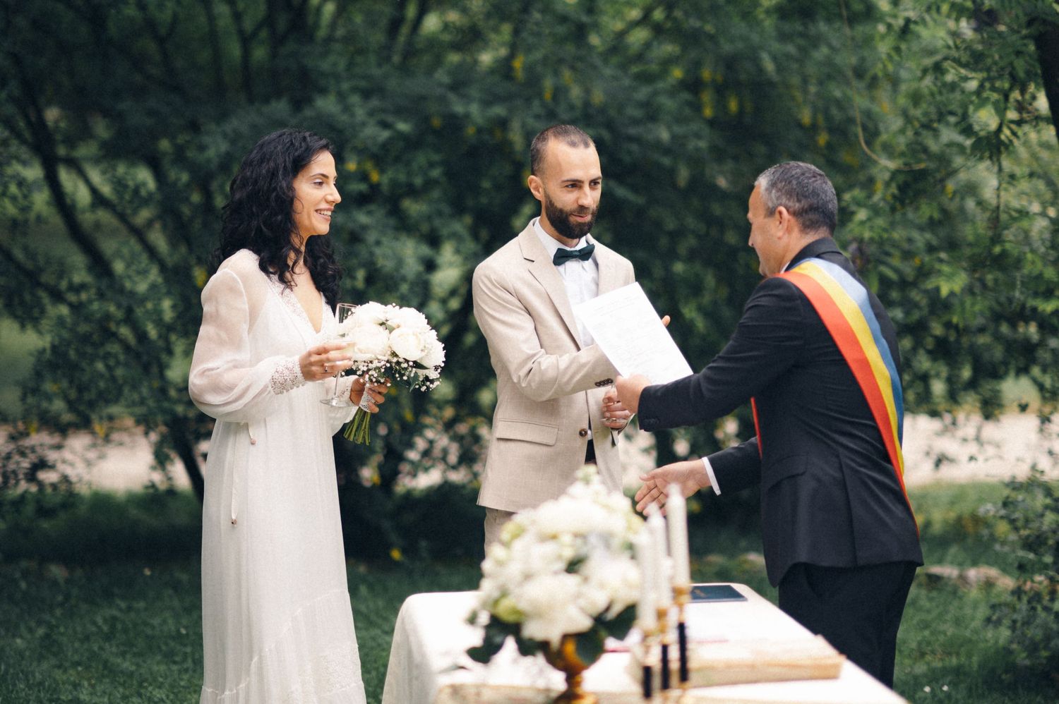 Outdoor wedding ceremony with couple and officiant standing at decorated table.