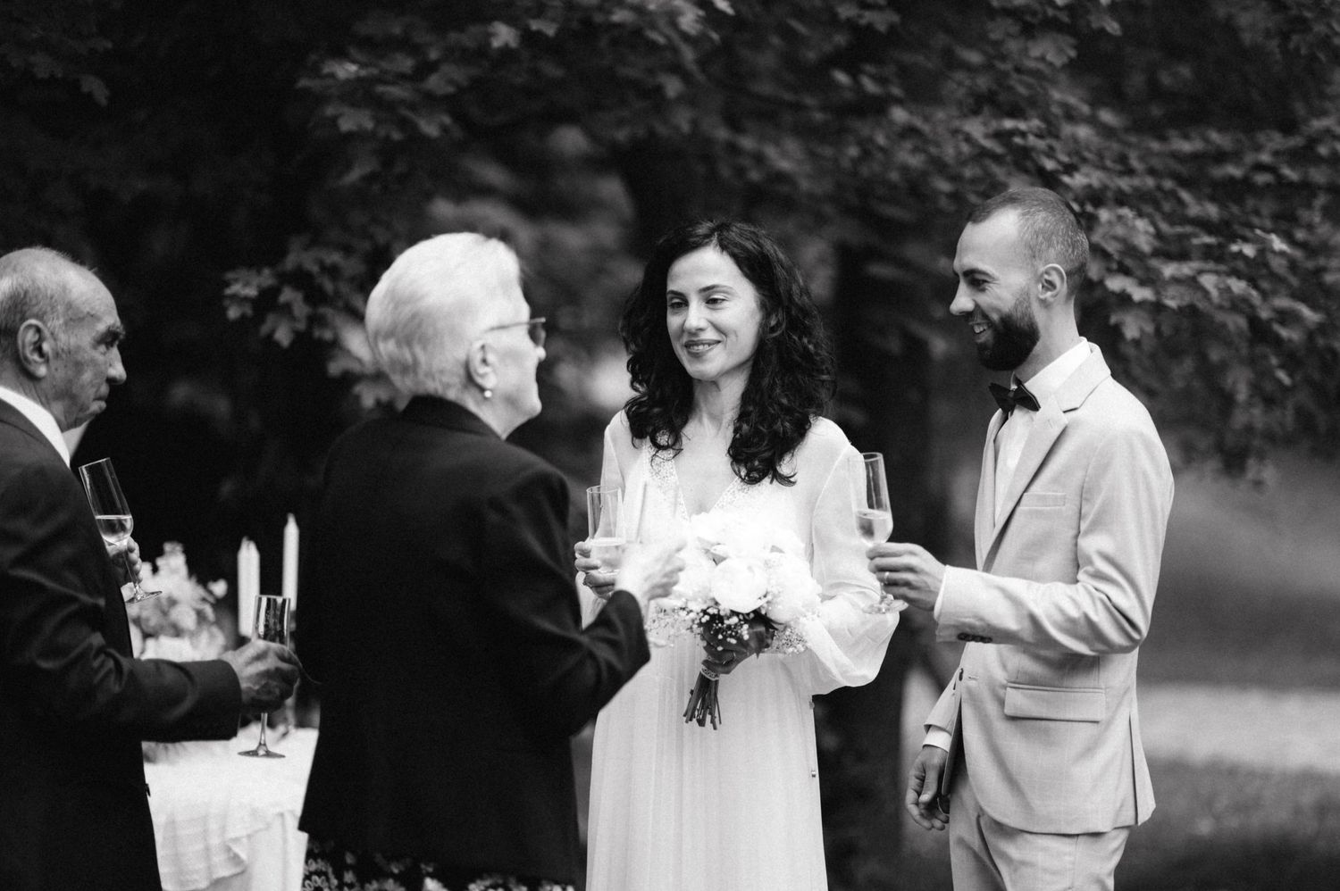 Black and white photo of wedding guests mingling during outdoor reception.