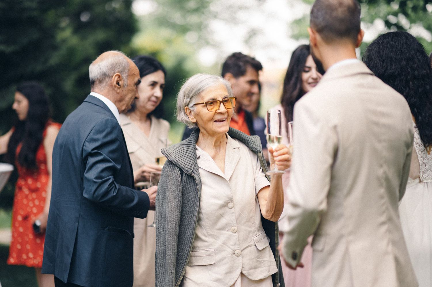 Guests mingling and holding champagne glasses at outdoor wedding reception.