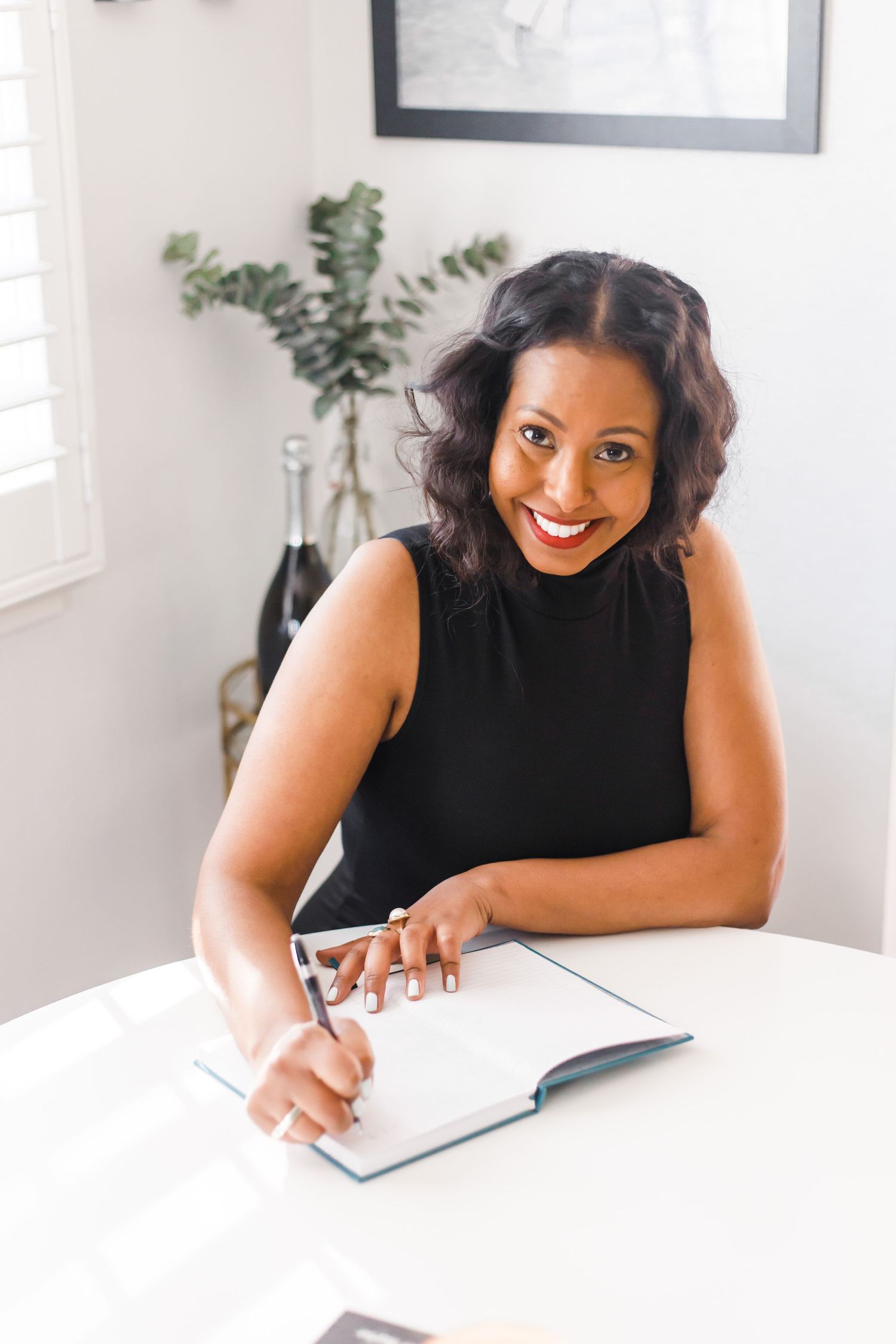 brand photo of a early-thirties black woman wearing a black top writing in a notebook