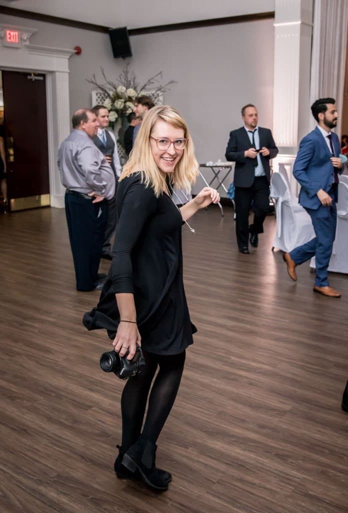 Professional photographer working at an event in a venue with hardwood floors.