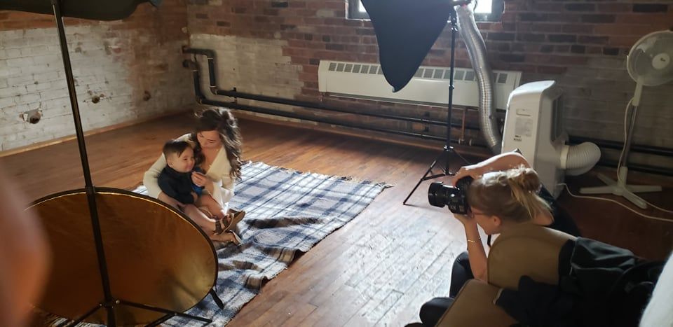 Behind the scenes photo shoot setup in brick-walled studio with lighting equipment.