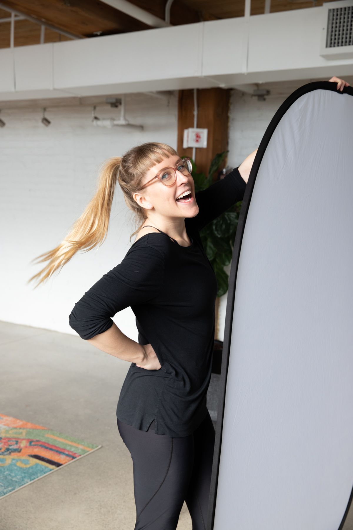 Photographer posing next to lighting equipment in studio space.