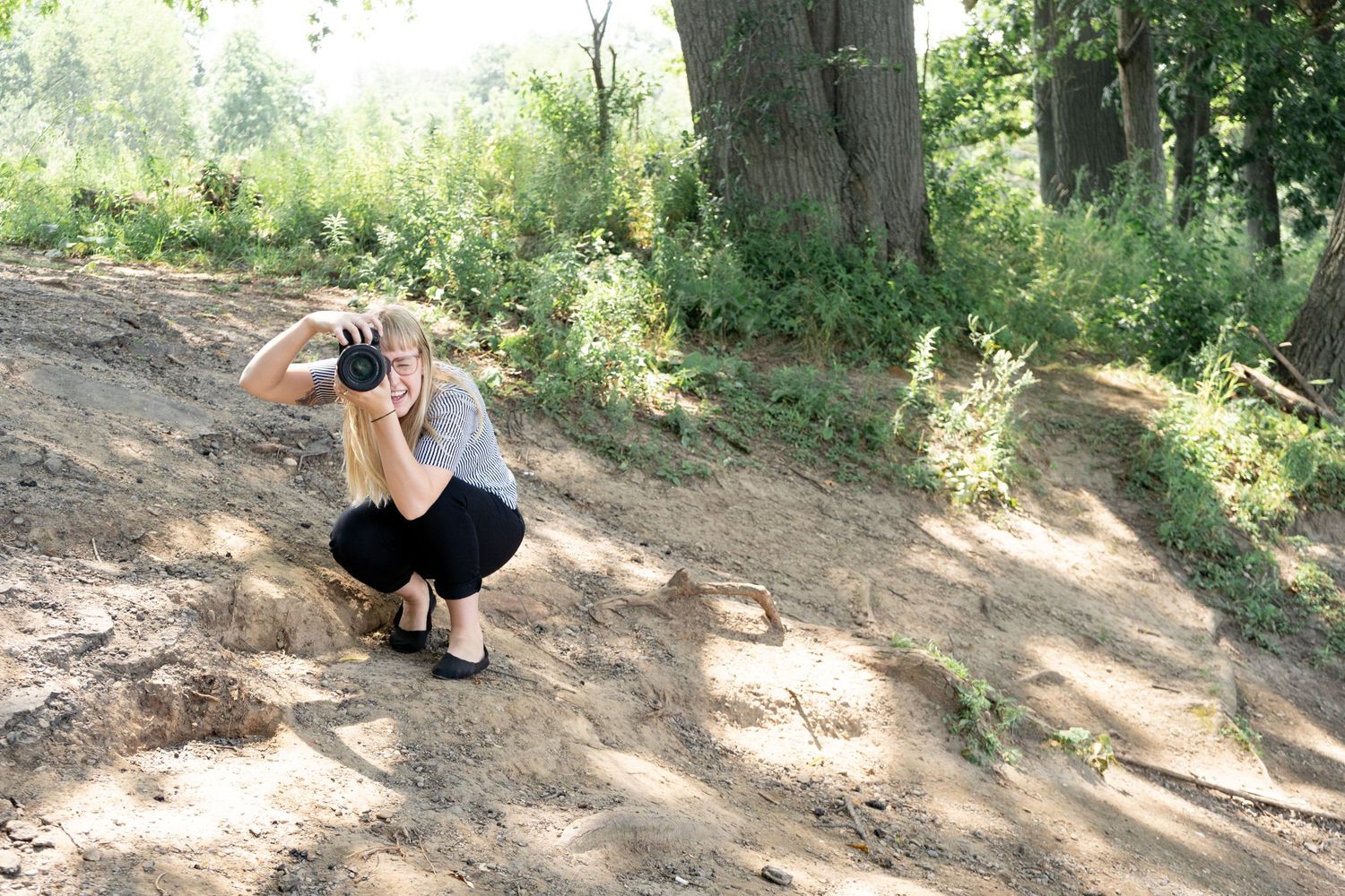 Photographer crouching to take creative angle shot on dirt path.