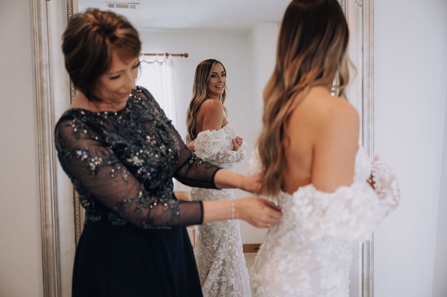 Final wedding dress preparations taking place in a light-filled dressing room.