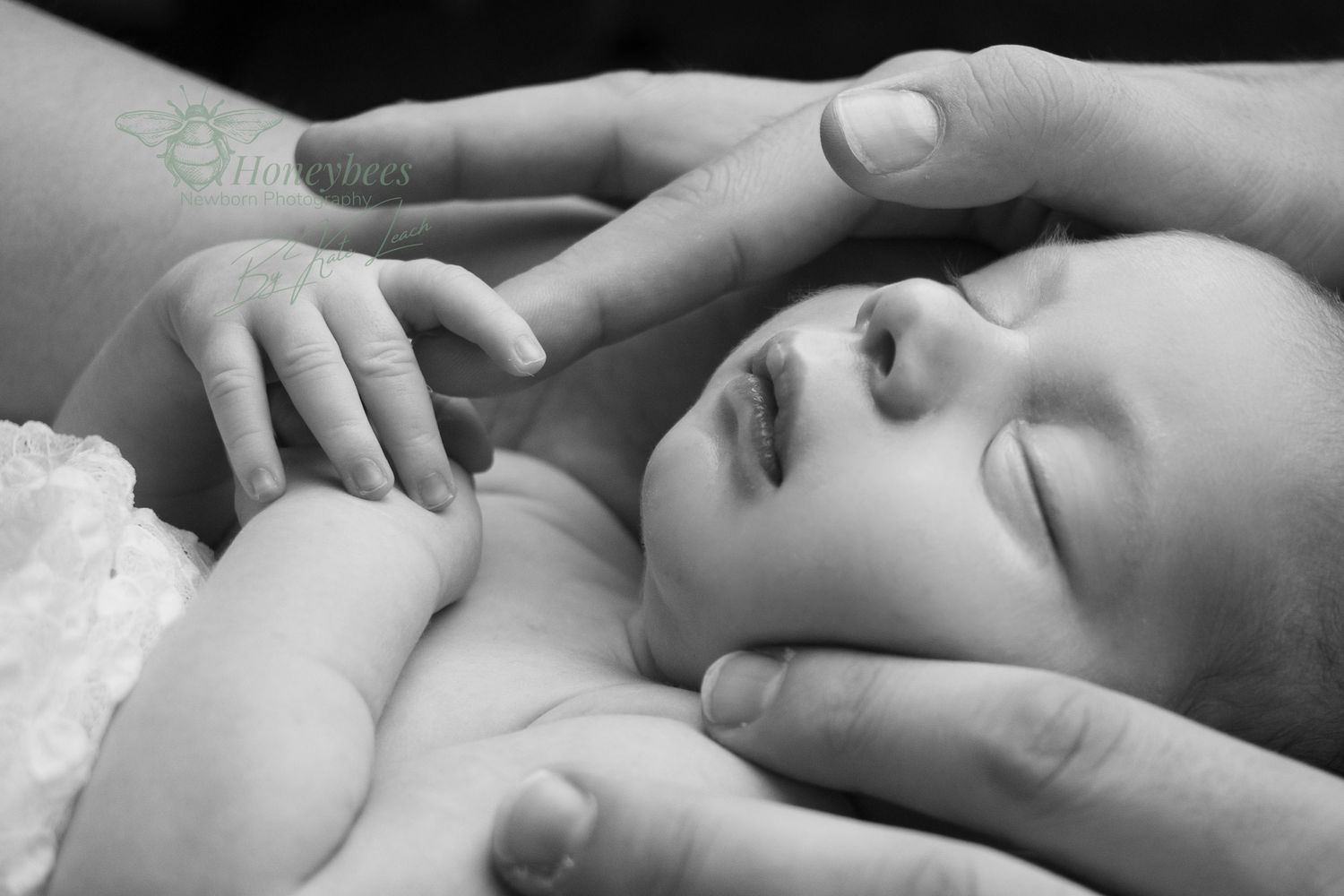 Newborn photoshoot of farther holding baby head, baby is grading dads finger loving.