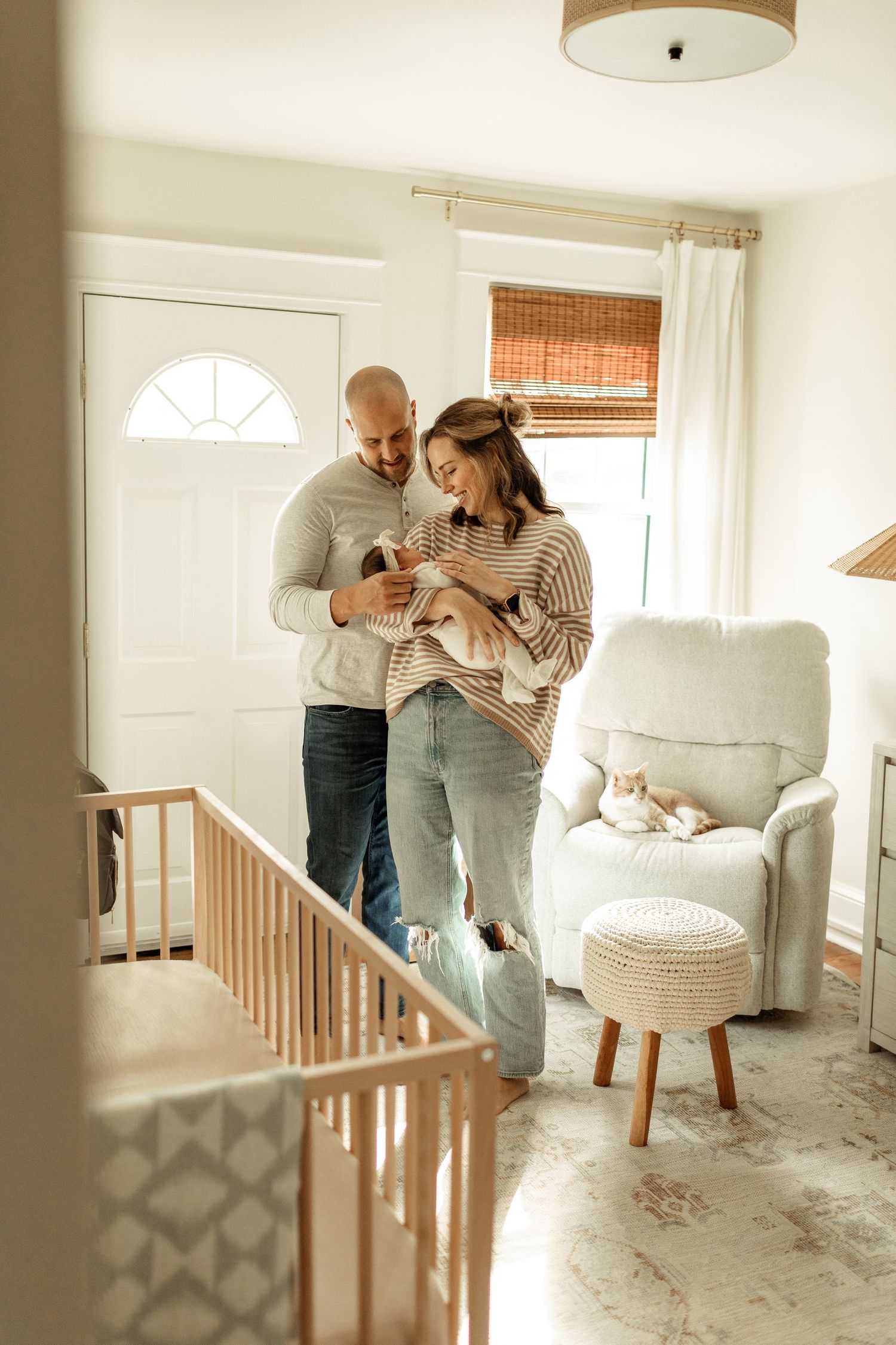 Couple standing in a nursery with natural light streaming through windows and modern decor.