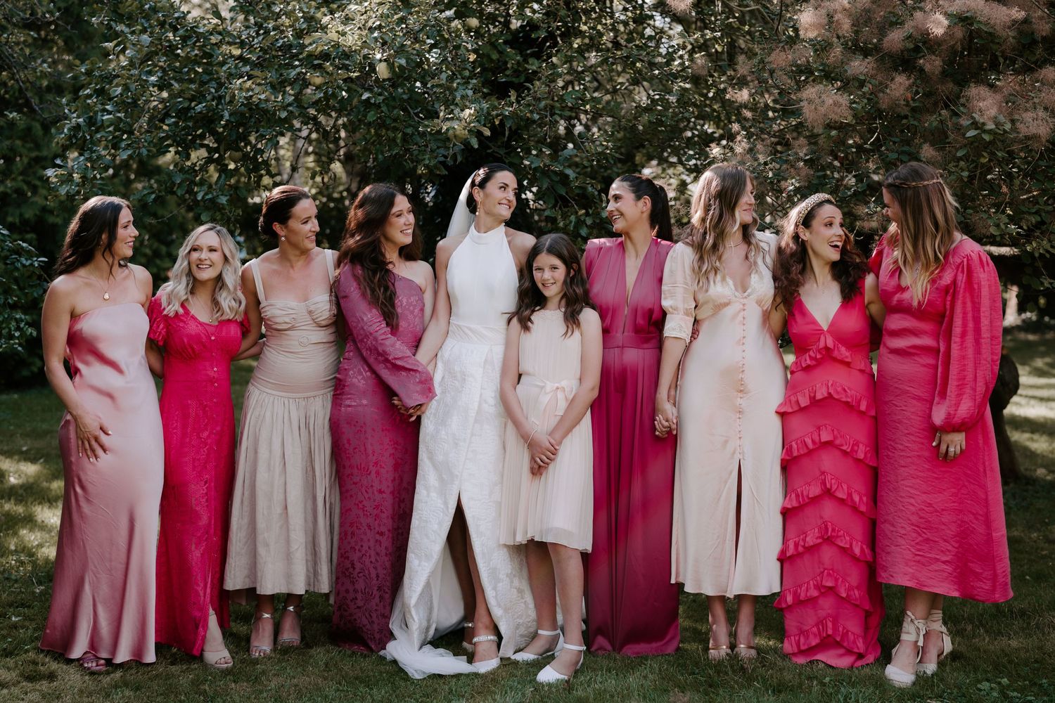 bride and bridesmaids stood in orchard laughing for a portrait in islip Oxfordshire