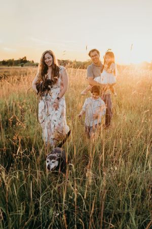Sunset family photo session in a tall grass field with their dog.