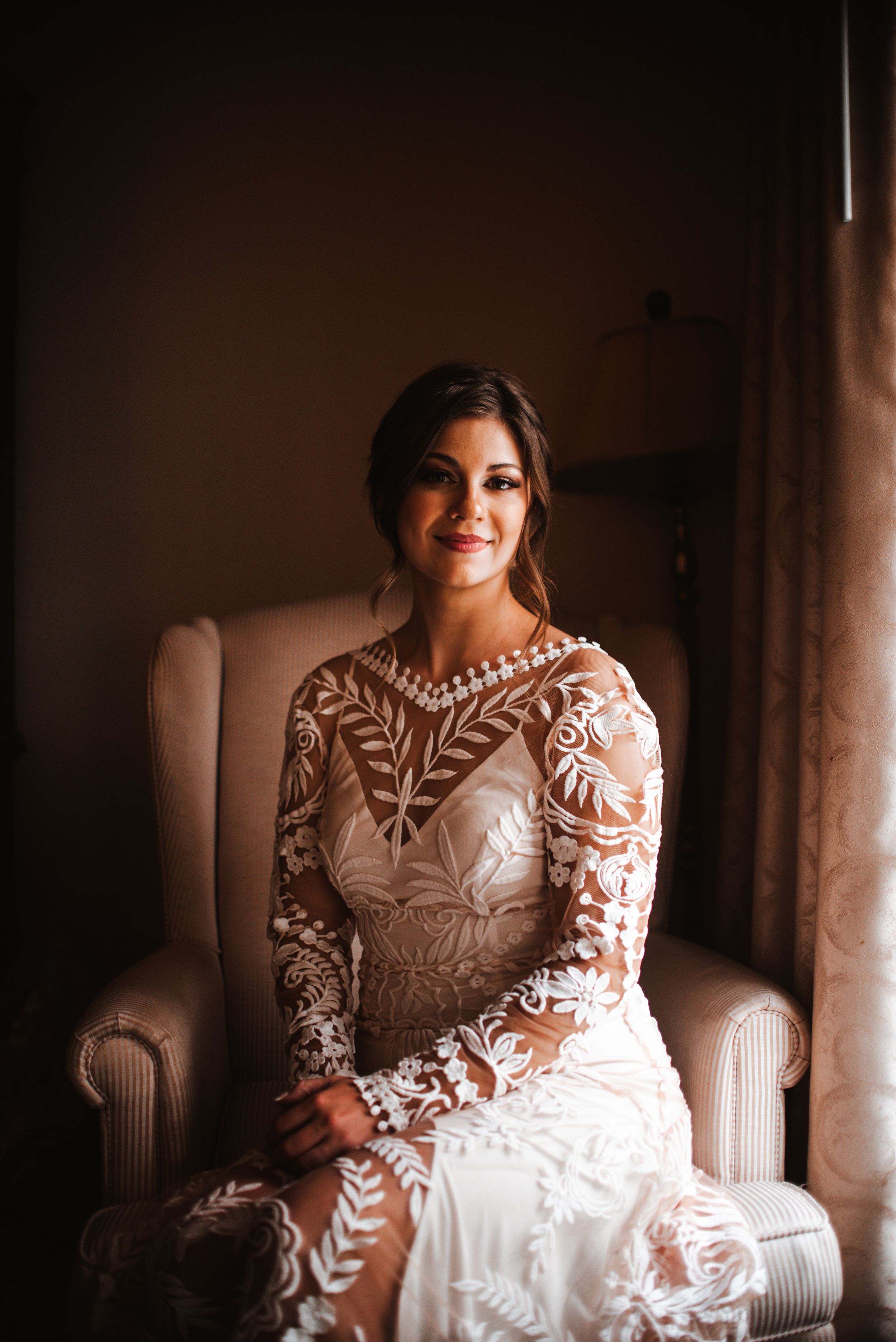 Elegant bridal portrait featuring intricate lace dress details in warm indoor lighting.