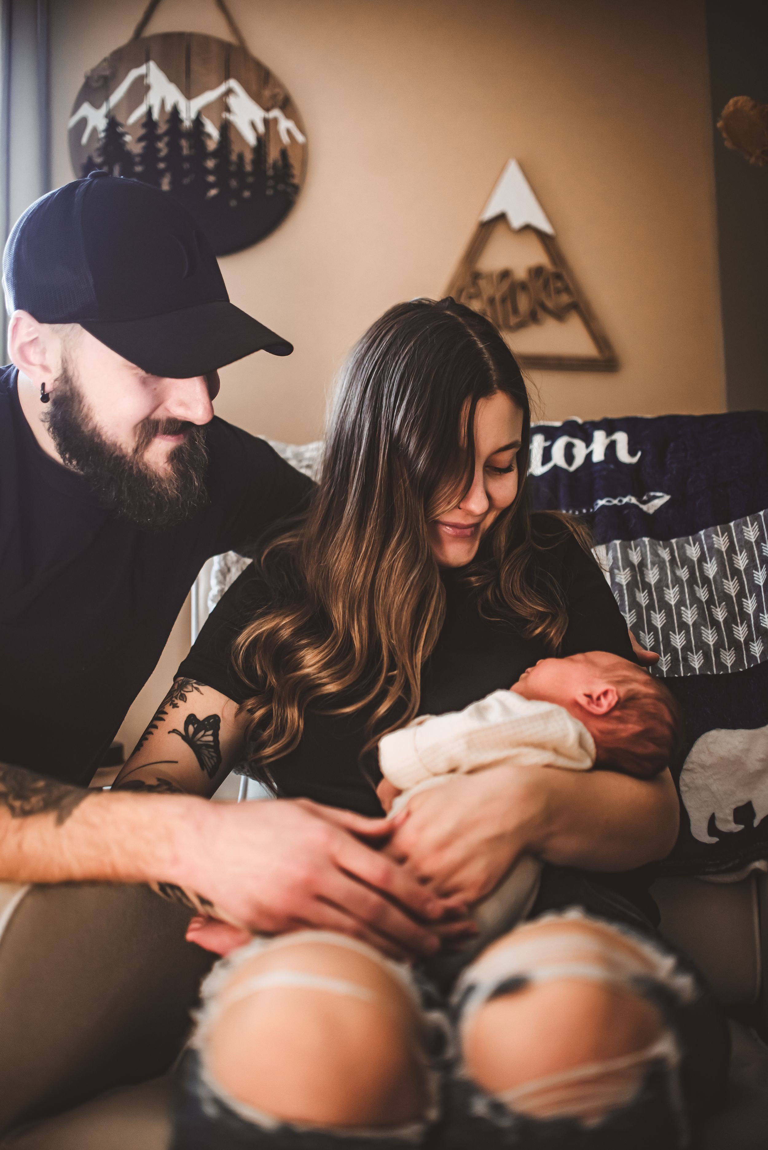 Family moment with newborn baby in cozy room with mountain wall art.