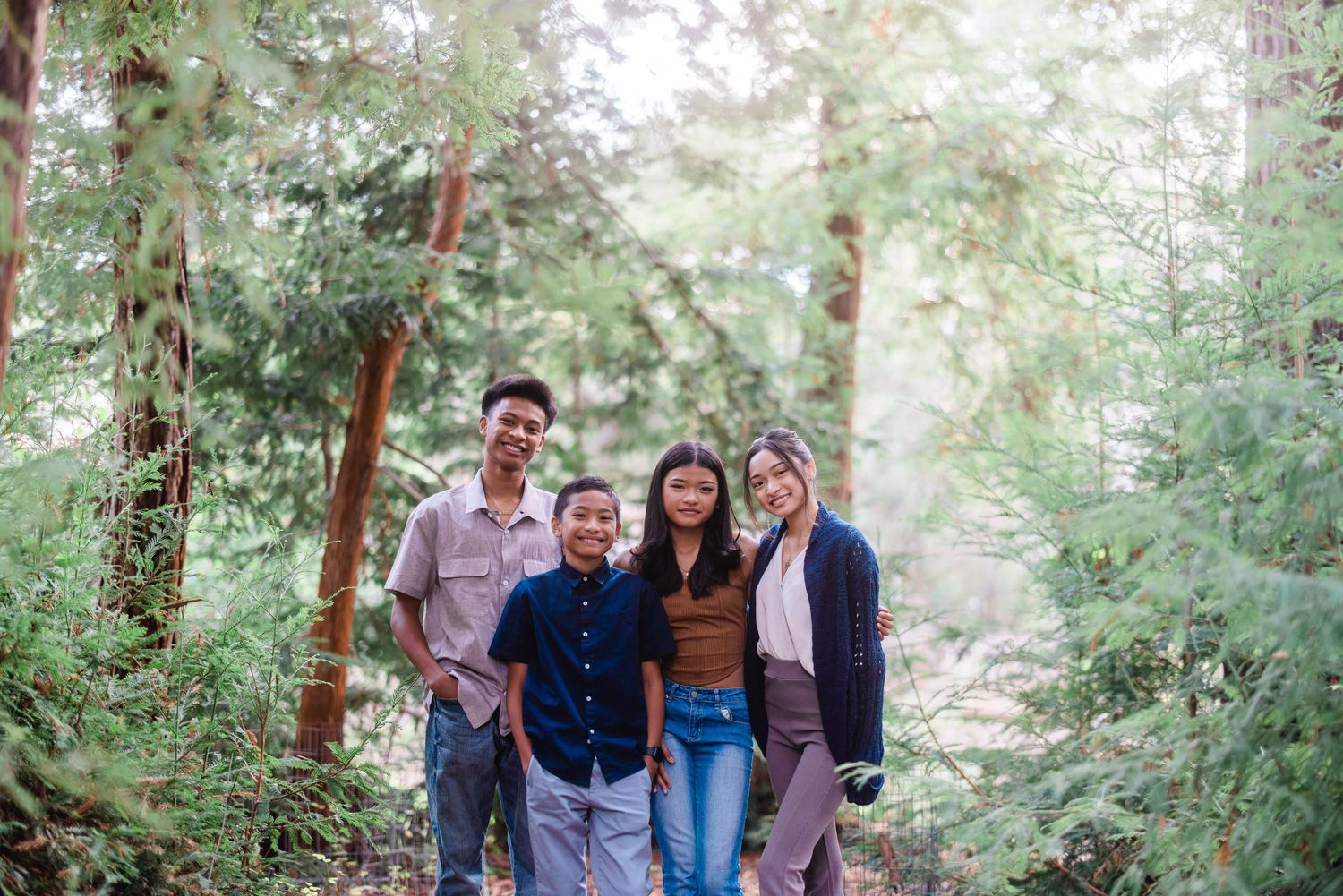 Group walking together on a wooded trail surrounded by tall trees and greenery.