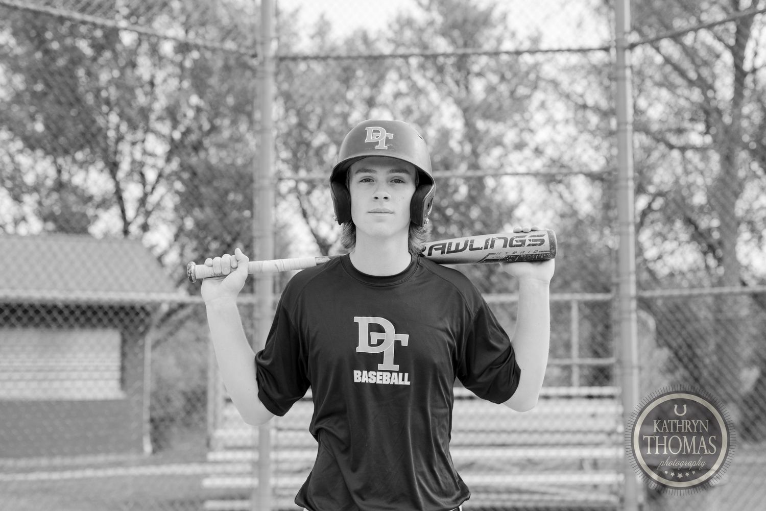 Baseball player poses with bat in black and white photography.