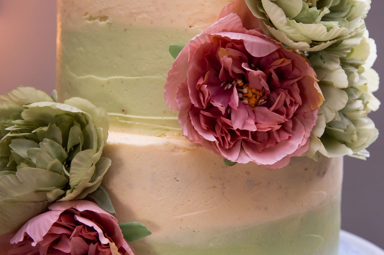 Wedding cake decorated with delicate pink and sage green floral accents.