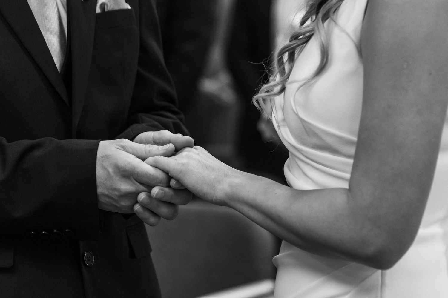 Black and white photo showing wedding ceremony close-up moments.