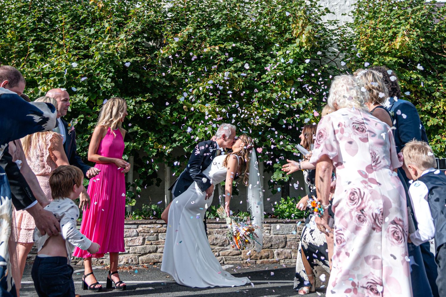 Joyful outdoor celebration with guests in floral dresses dancing.