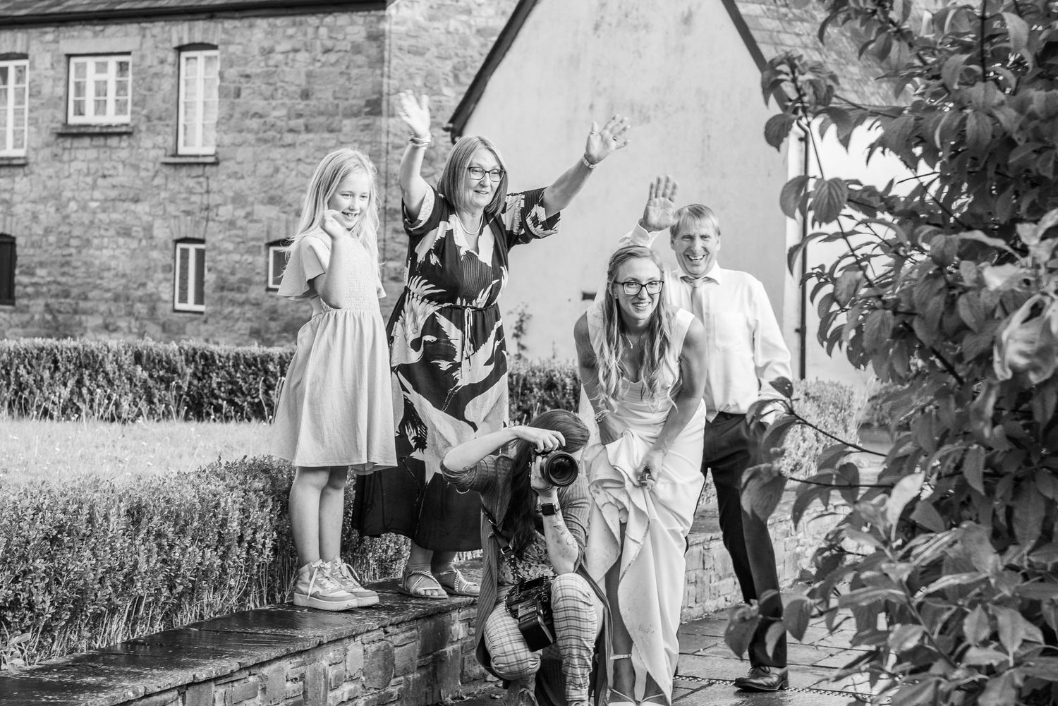Wedding party having fun while walking through garden pathway.
