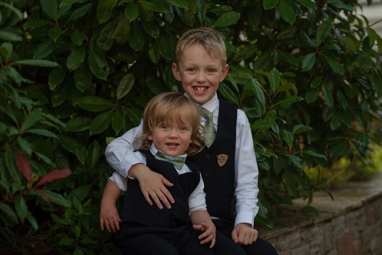 Young children pose in formal attire at an outdoor wedding venue.